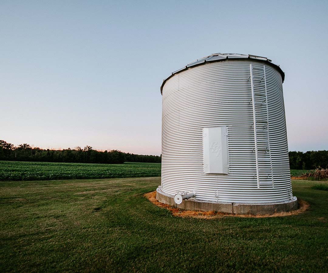 Large white water tower in an open field