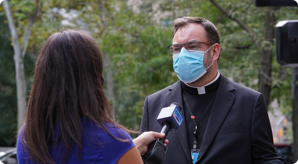 News reporter interviewing a clergyman who is wearing a mask