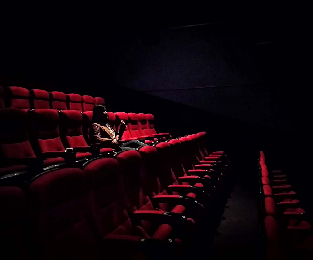 Woman sitting alone in movie theater red chair