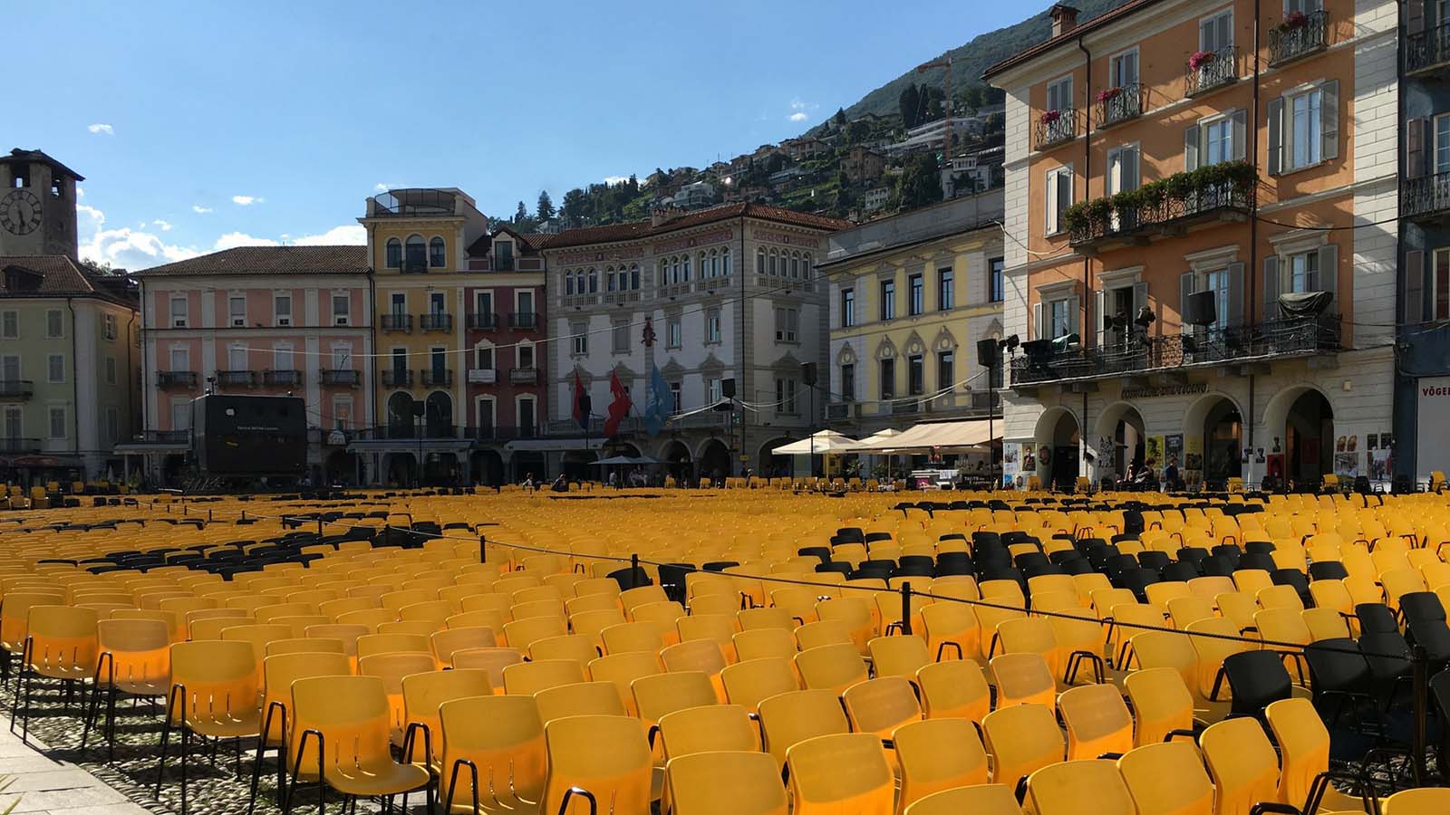 Several rows of empty yellow chairs in a square in Locarno, Switzerland